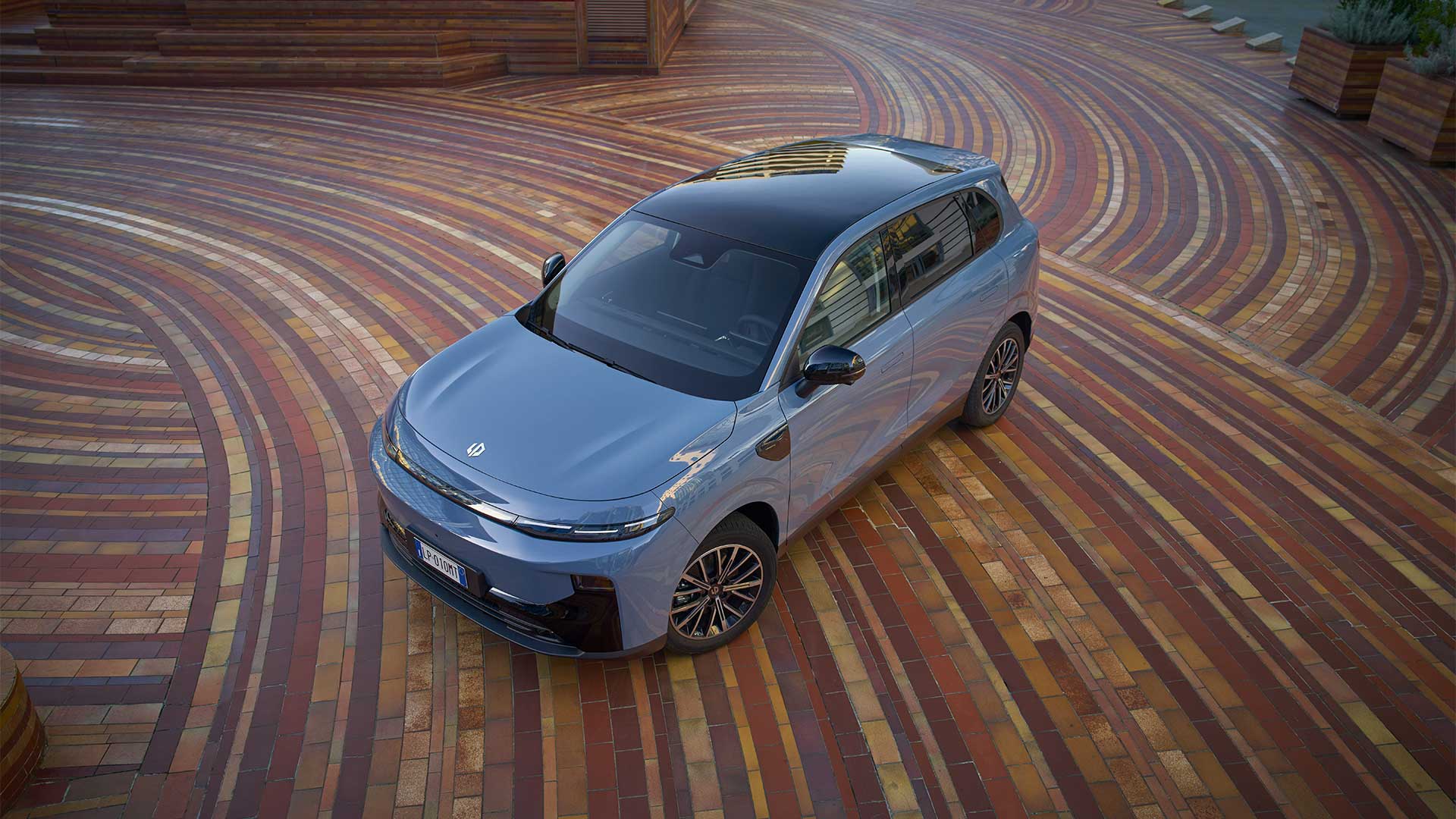 Vista superior de Leapmotor B10 azul estacionado en una plaza contemporánea con pavimento de mosaico.